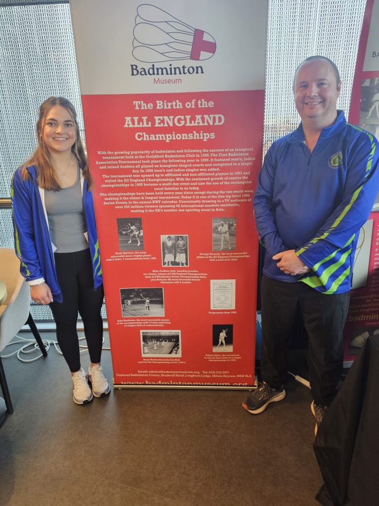 Freya Redfearn Badminton Player standing in front of a Badminton Museum Banner with Mike one from the Badminton Museum Board